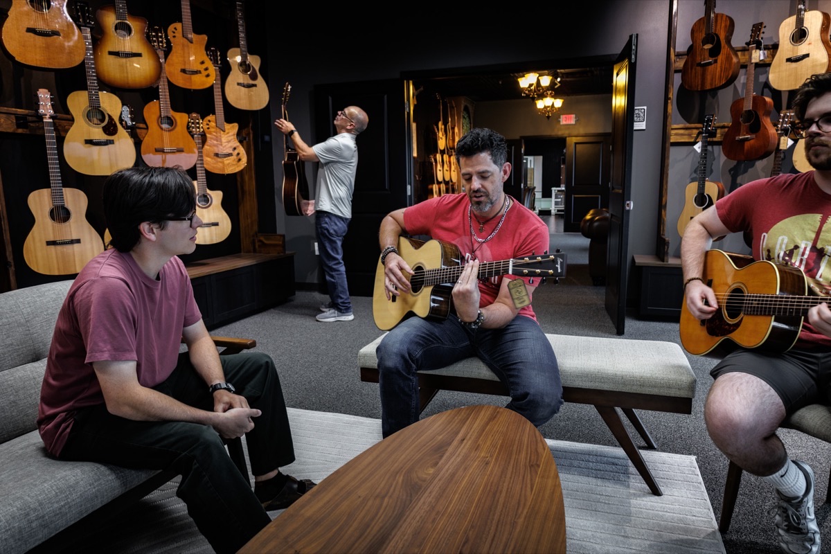 Musicians playing acoustic guitars together in the Corzic Music showroom lounge