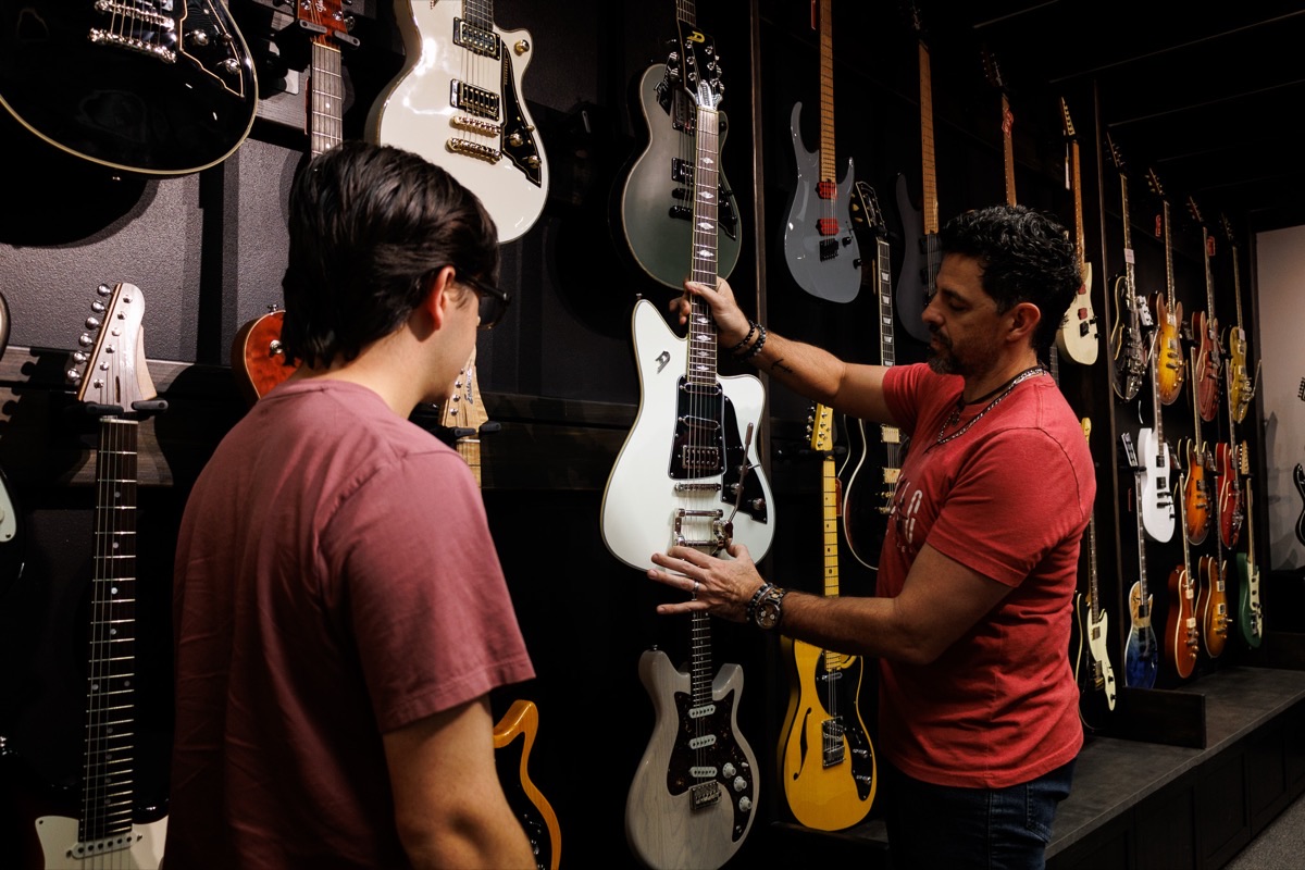 A Corzic Music team member showing an electric guitar to a customer in the showroom